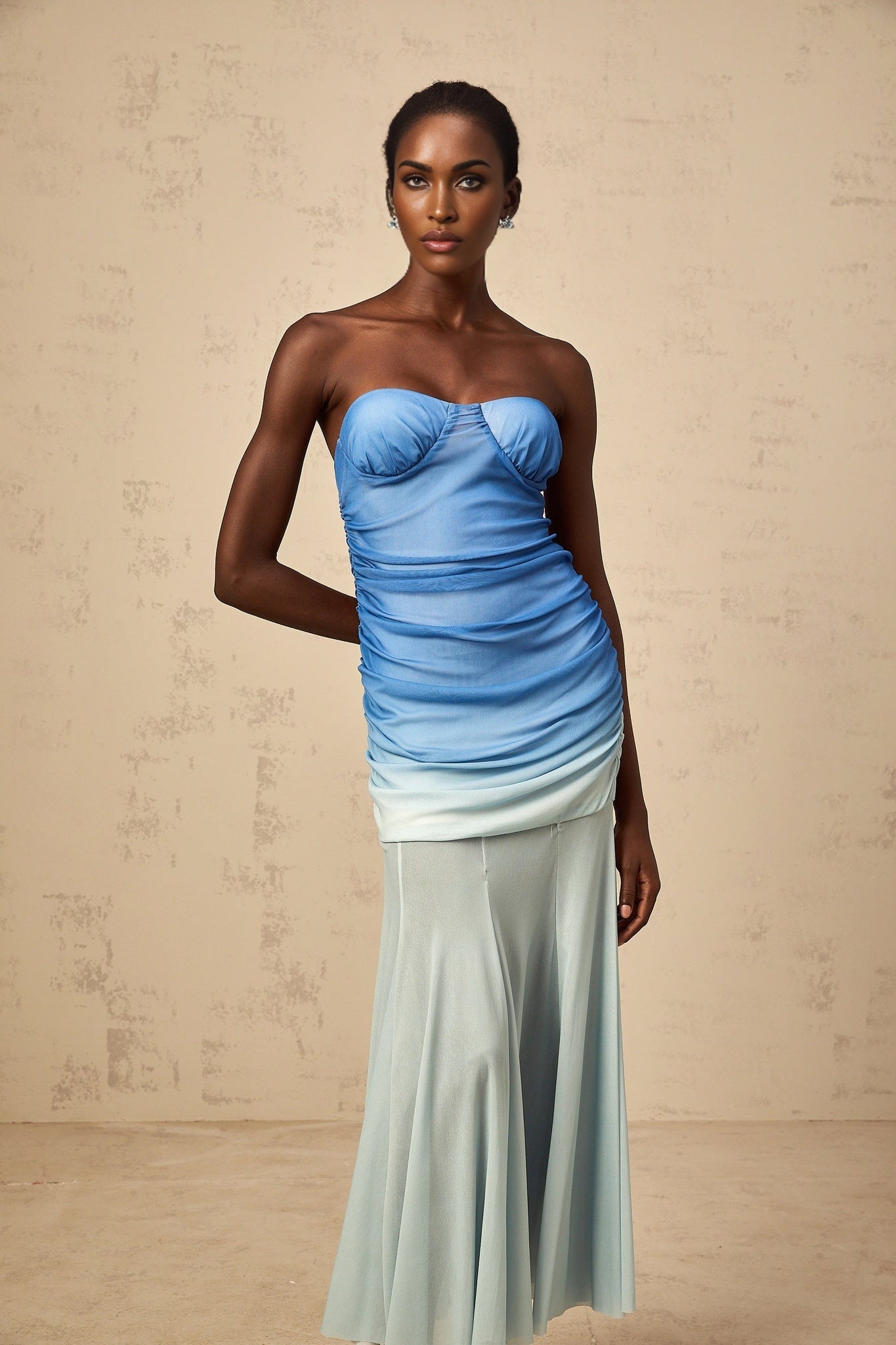 Woman wearing a blue gradient mesh midi dress with sheer fabric and ombre effect from light to dark blue