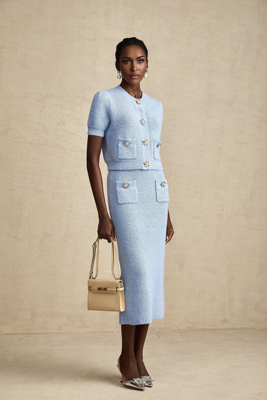 Woman wearing a blue knit matching set consisting of a blouse and skirt