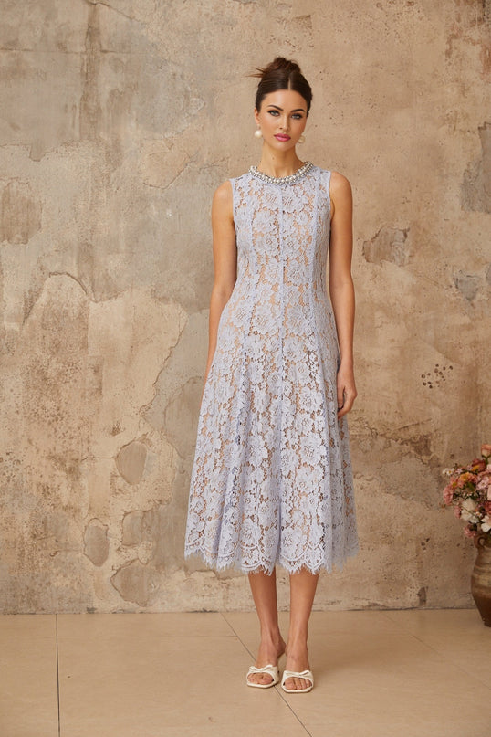 Woman wearing a blue midi dress with floral lace pattern and embellishments