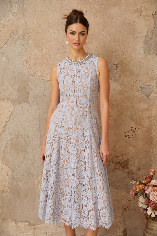 Woman wearing a blue midi dress with floral lace pattern and embellishments