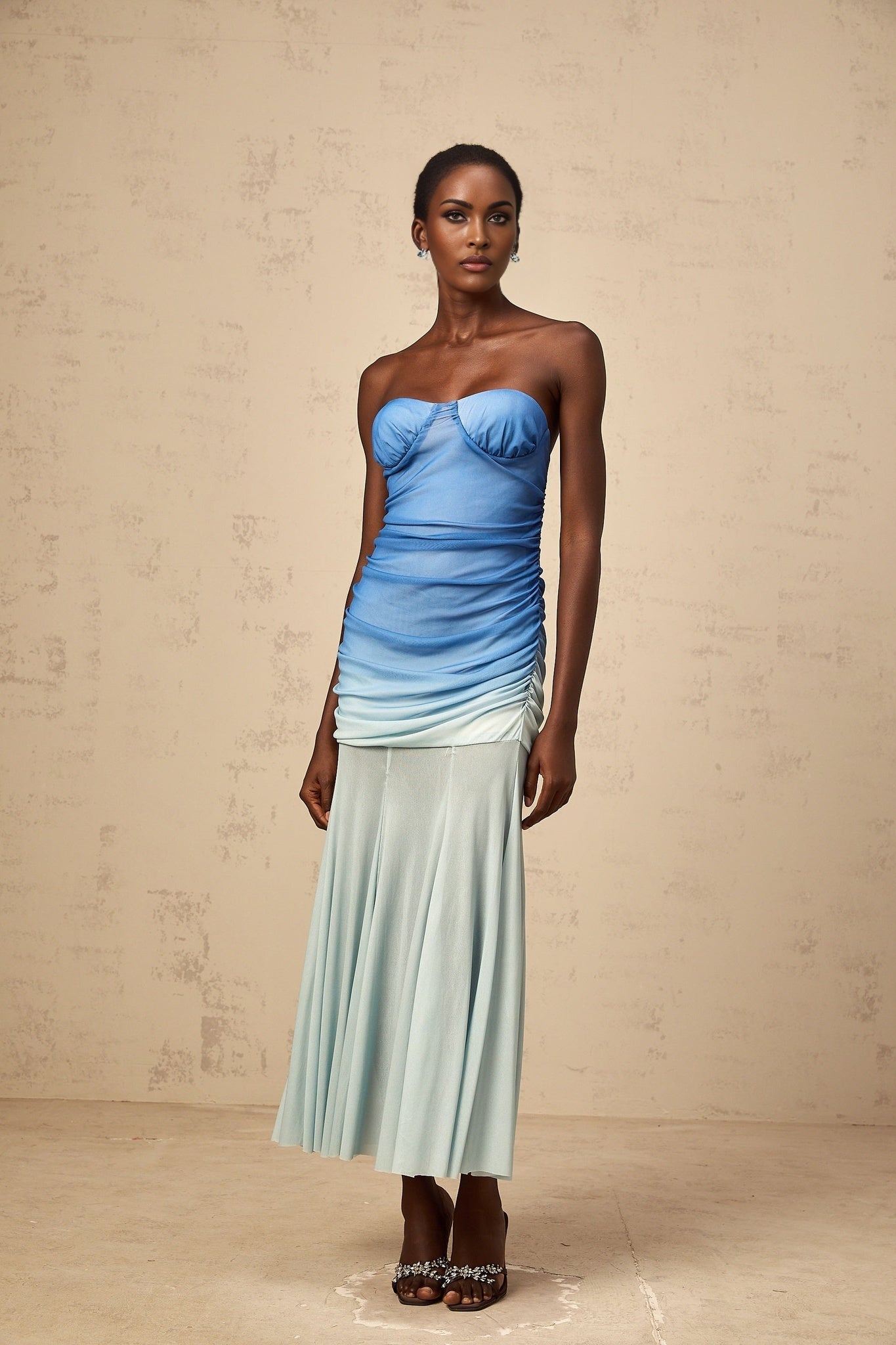 Woman wearing a blue ombre midi dress with mesh overlay standing against a plain background