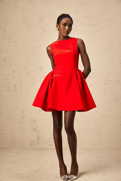 Woman wearing a bright red sleeveless mini dress with a flared skirt standing against a plain background