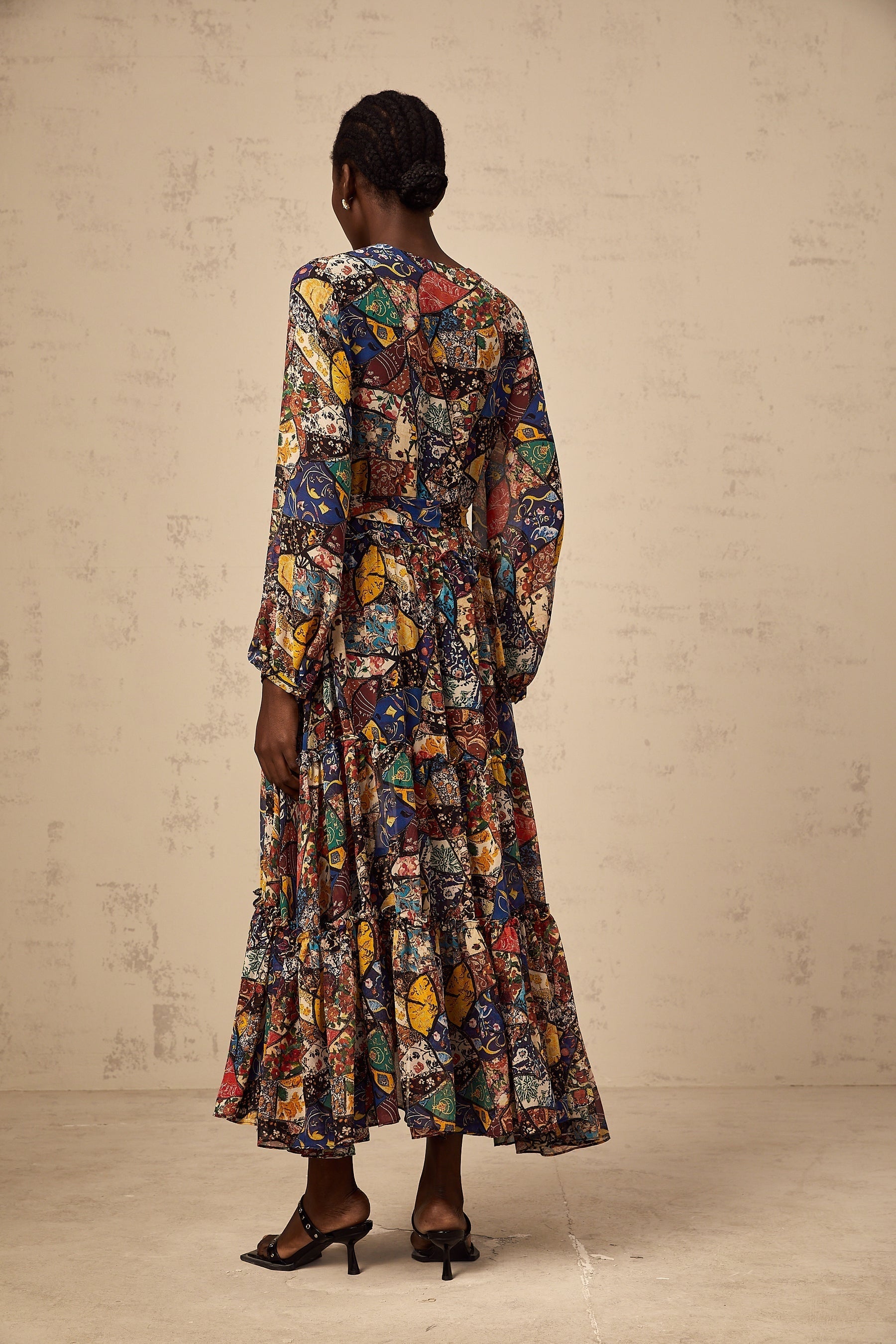 Woman wearing a brown bohemian style midi dress with shirring details and flowy sleeves in an outdoor setting