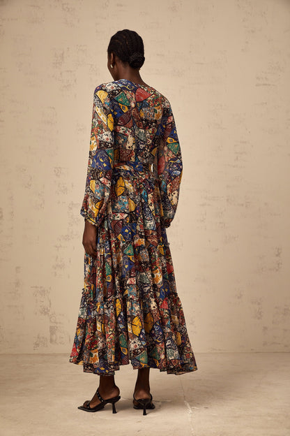 Woman wearing a brown bohemian style midi dress with shirring details and flowy sleeves in an outdoor setting