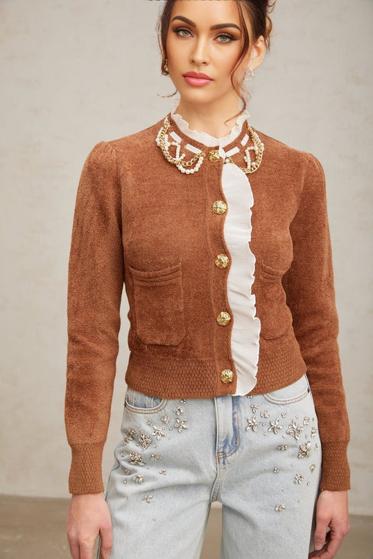 Woman wearing a brown knit cardigan with embellished details and ruffled trim