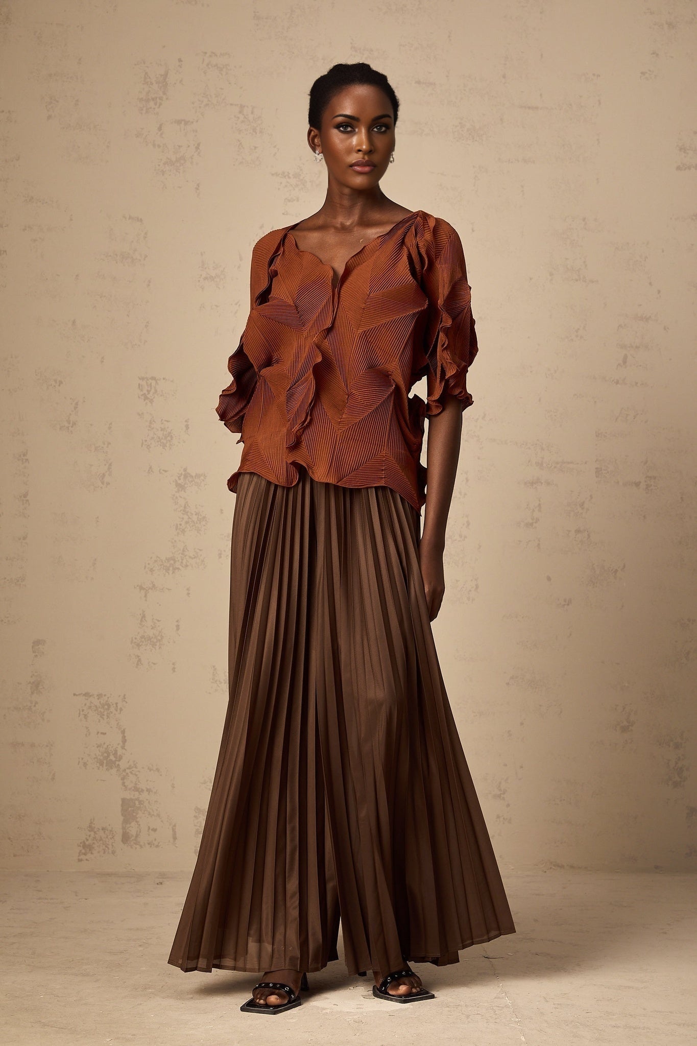 Woman wearing a brown matching set consisting of a creased top and skirt in demi style