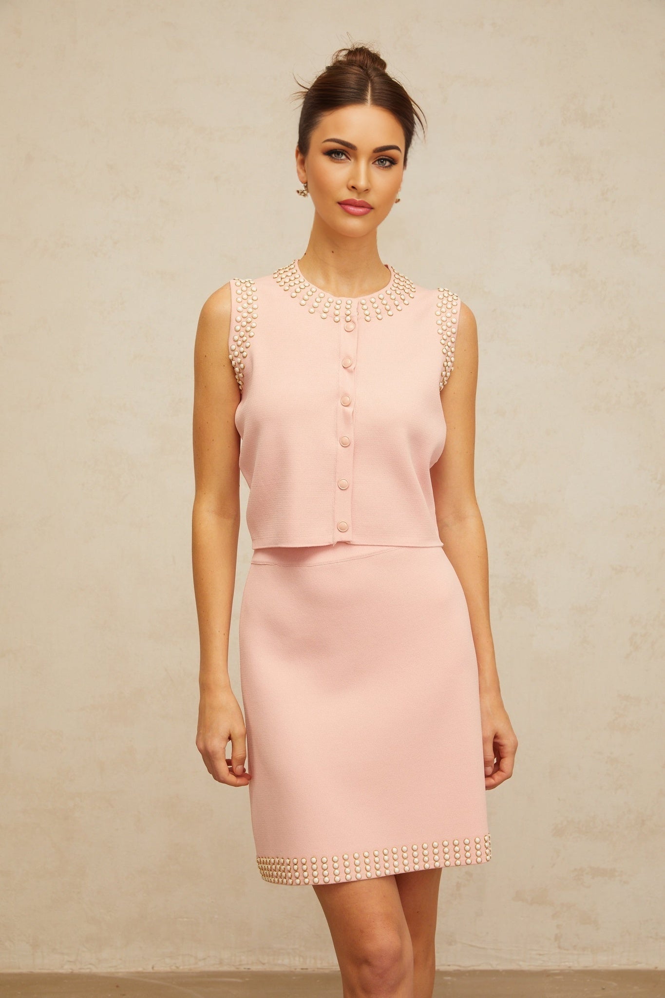 Woman wearing a cerise pink matching set consisting of a beaded knit top and skirt