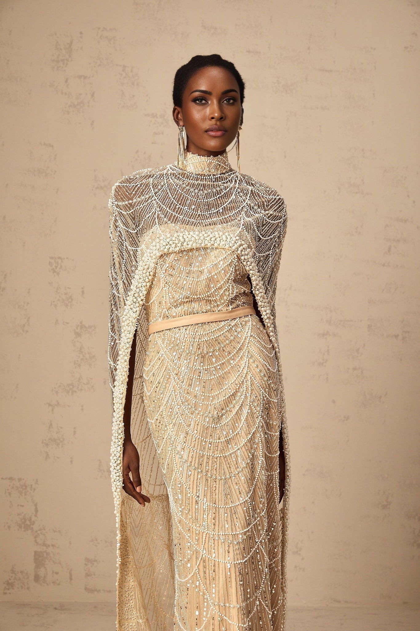 Woman wearing a champagne colored beaded gown with matching cape elegant formal attire for special occasions