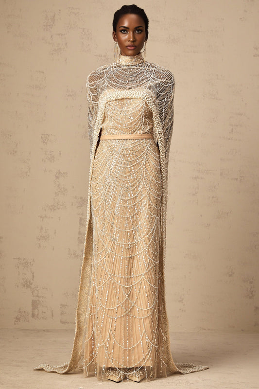 Woman wearing a champagne colored beaded gown with matching cape elegant formal attire