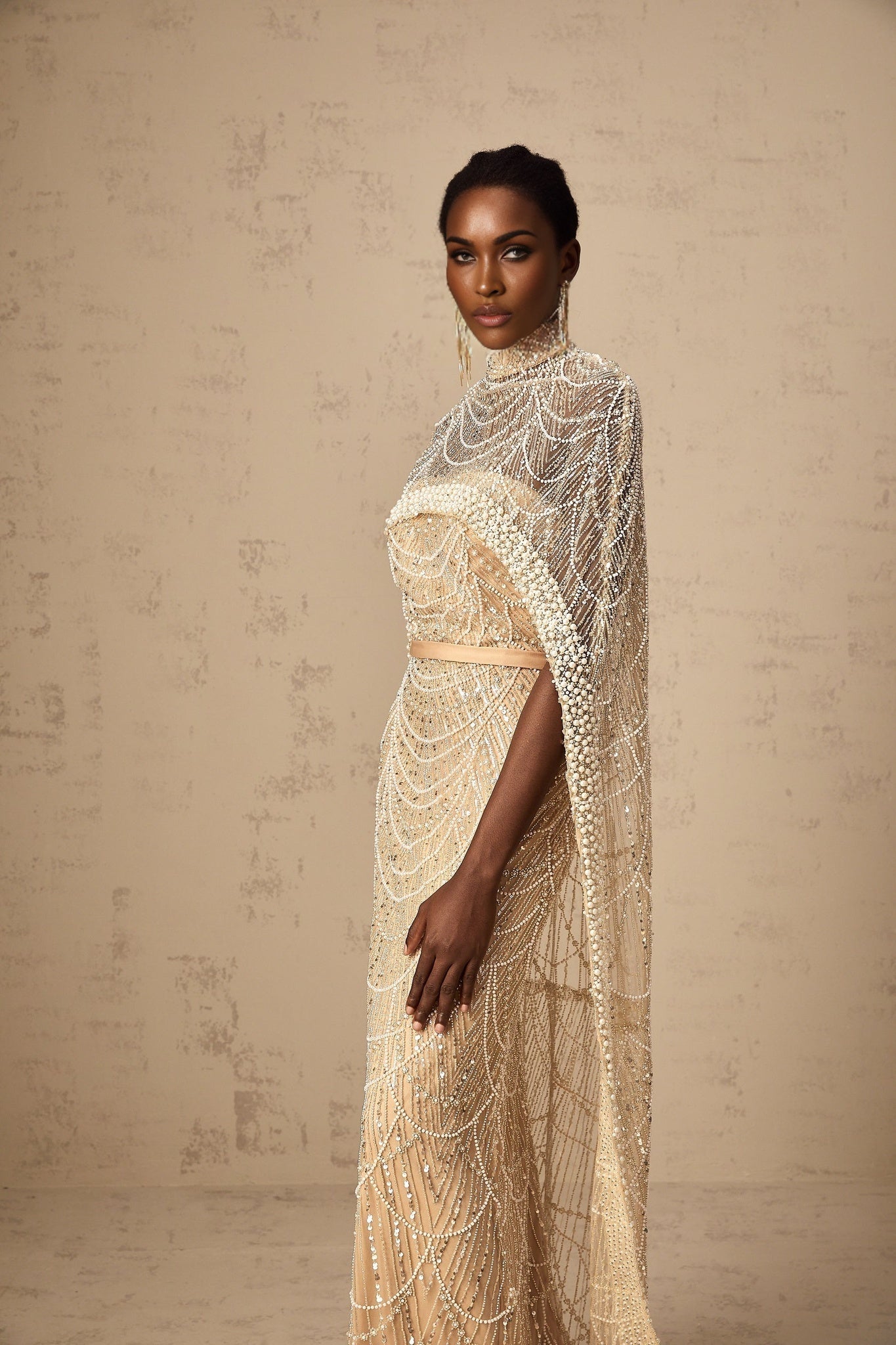 Woman wearing a champagne colored beaded gown with matching cape elegant formal evening attire