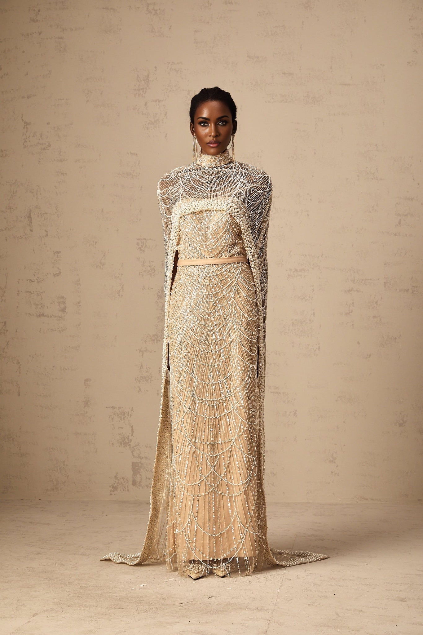 Woman wearing a champagne colored beaded gown with matching cape
