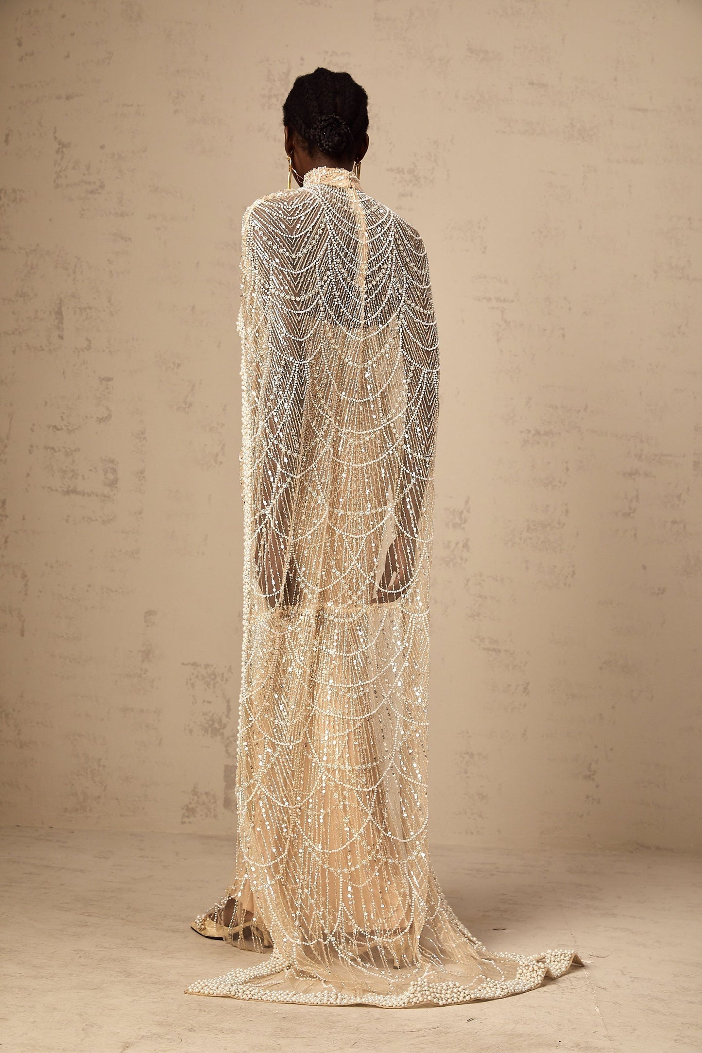 Woman wearing a champagne colored gown with matching beaded cape set named Frederica