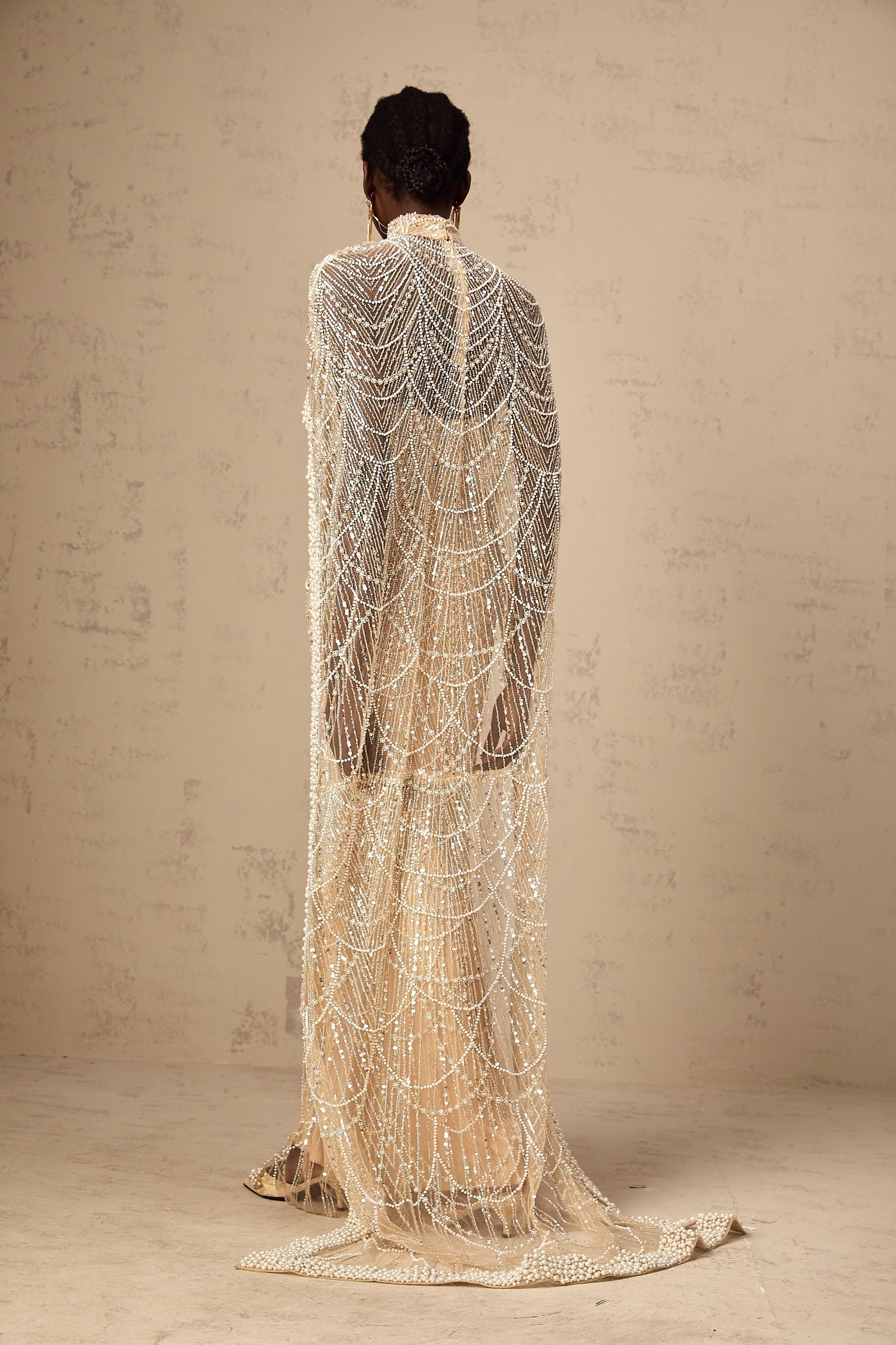 Woman wearing a champagne colored gown with matching beaded cape set named Frederica