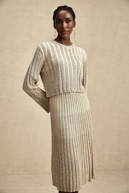 Woman wearing a champagne colored striped knit top and matching skirt set