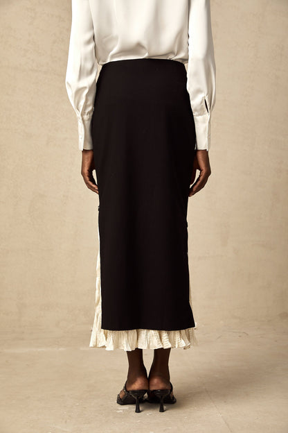 Woman wearing a colorblocked midi skirt with contrasting panels in different colors standing against a plain background