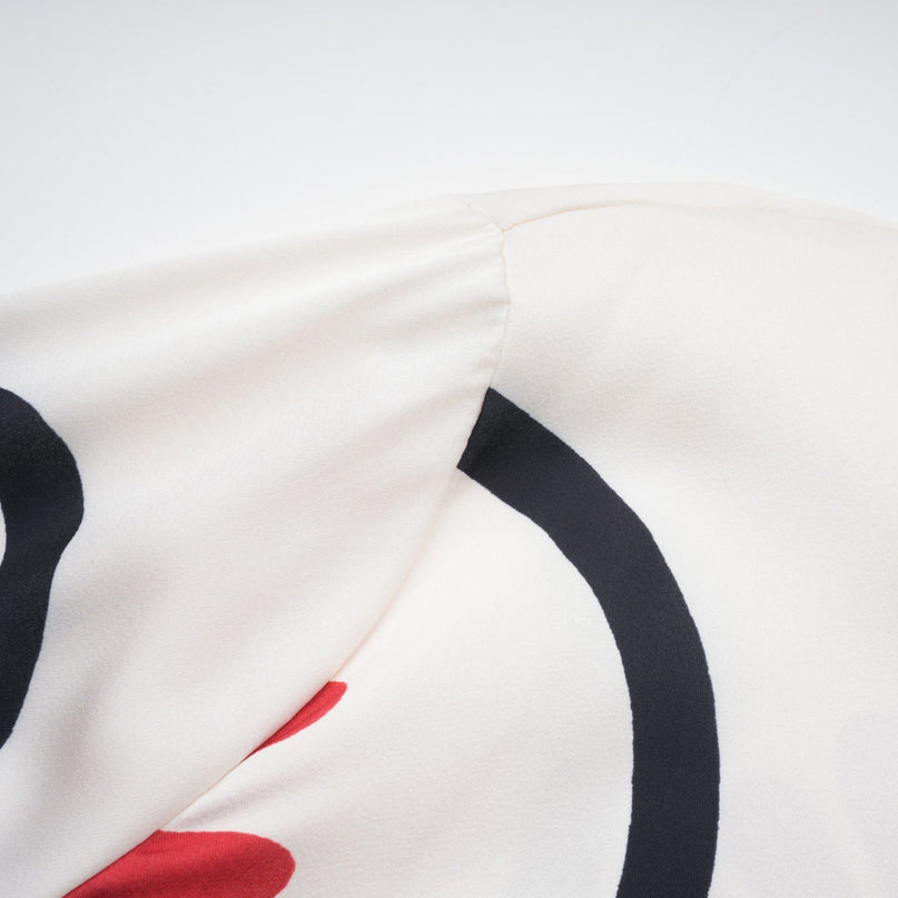 Woman wearing a colorful matching set with a graphic print shirt and trousers in vibrant Amaranta design