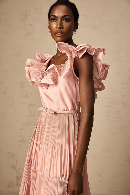Woman wearing a coralpink midi dress with pleated details and frilled accents Standing pose showing full length of the dress