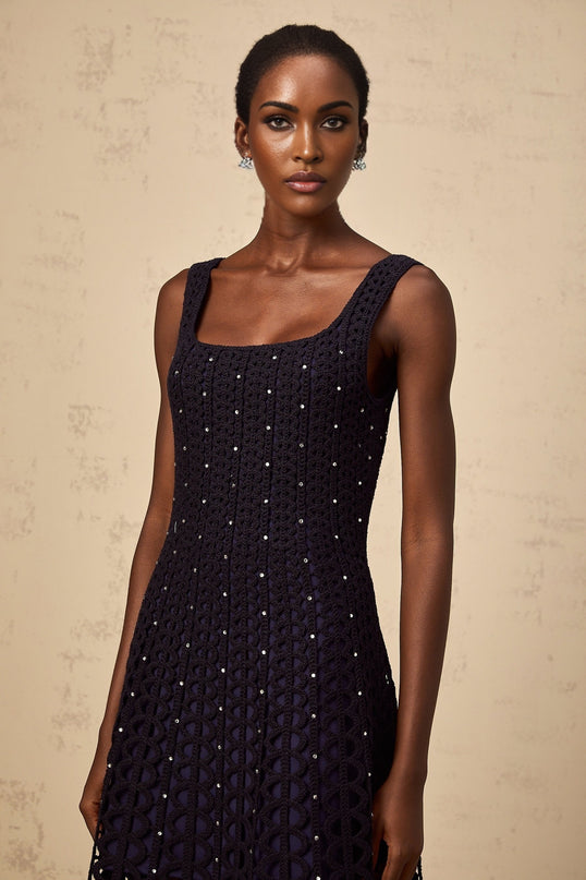 Woman wearing a dark blue mini dress with embellished details and crochet knit pattern featuring cutout design
