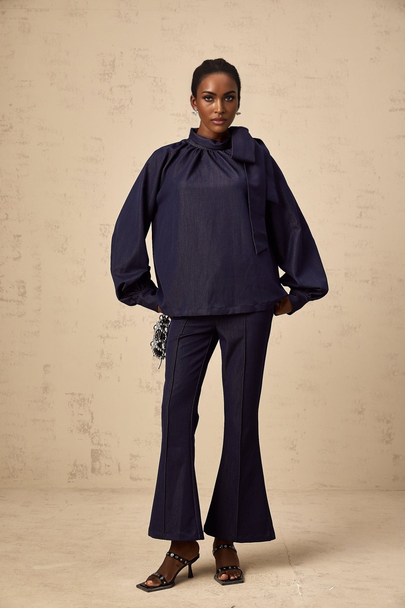 Woman wearing a denim blue matching set consisting of a flared blouse and trousers named Mathilde