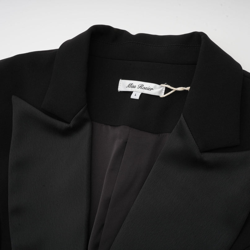 Woman wearing a fitted black blazer dress with single breasted closure and tailored silhouette