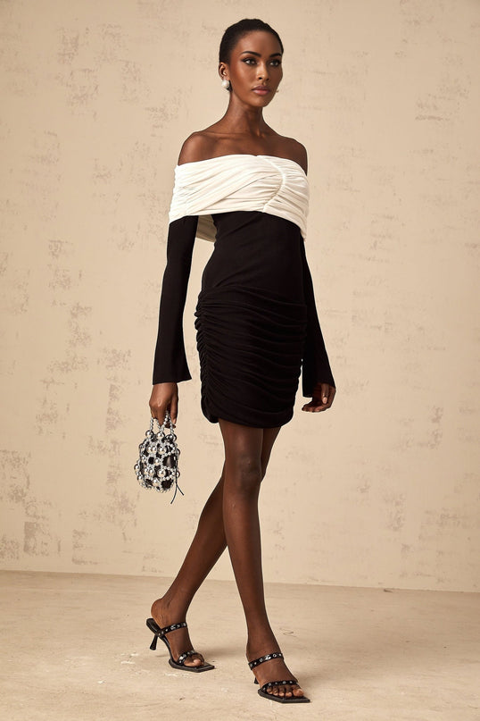 Woman wearing a fitted mini dress with color block design and ruched detailing