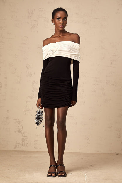 Woman wearing a fitted mini dress with colorblocked design and ruched details