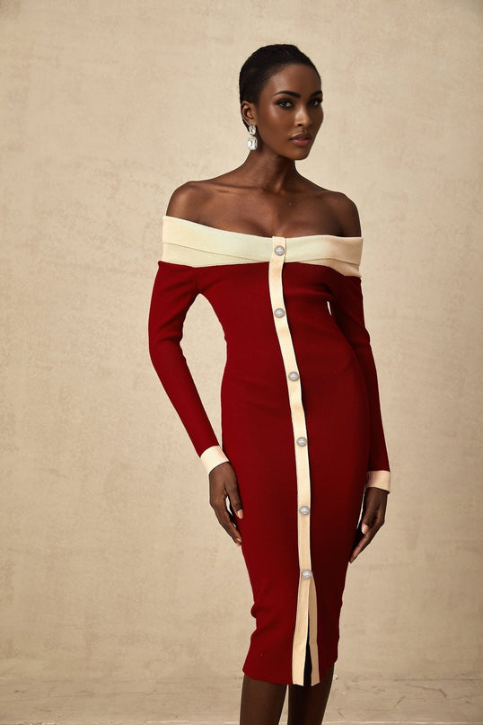 Woman wearing a fitted offshoulder midi dress in a knit fabric standing against a plain background