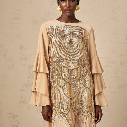 Woman wearing a floorlength tulle dress with sequin embellishments and ruffle sleeves in a formal setting