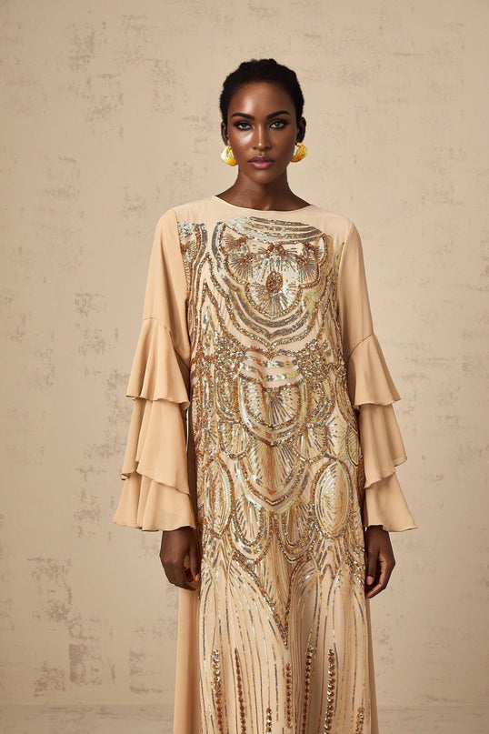 Woman wearing a floorlength tulle dress with sequin embellishments and ruffle sleeves in a formal setting