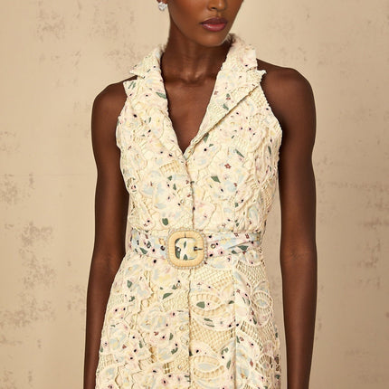 Woman wearing a floral embroidered midi dress with cut out details against a plain background