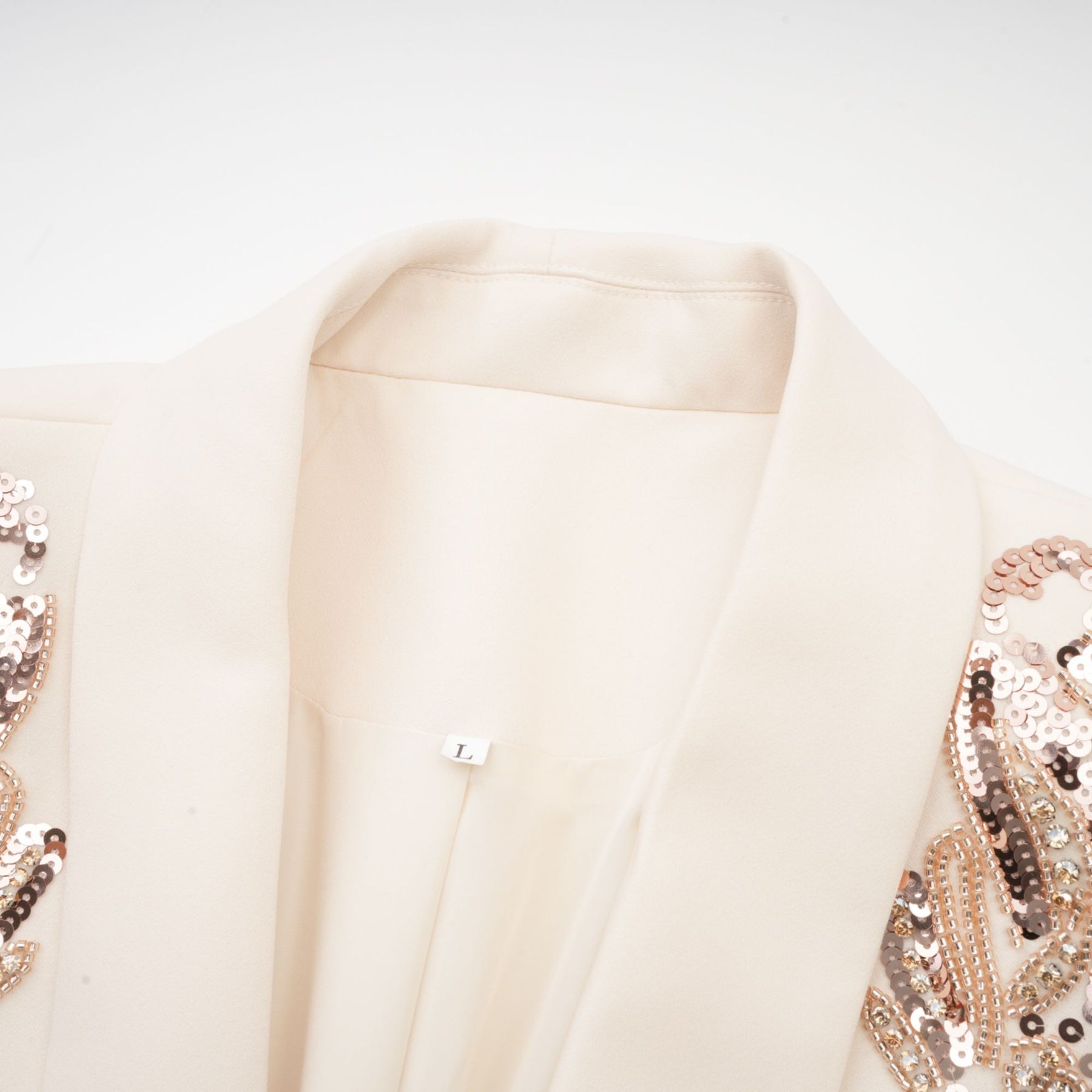 Woman wearing a formal blazer dress with sequin embellishments and sparkly details