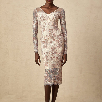 Woman wearing a formfitting white midi dress with intricate guipure lace pattern standing in elegant pose