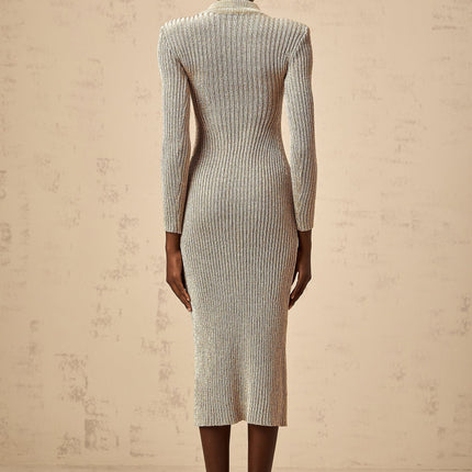 Woman wearing a gold ribbed knit midi dress with pointelle detailing standing in front of a plain background