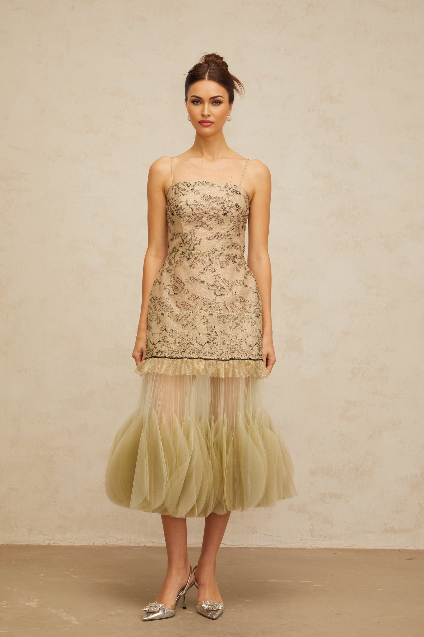 Woman wearing a green midi dress with embroidered details and panelled design named Mathilde