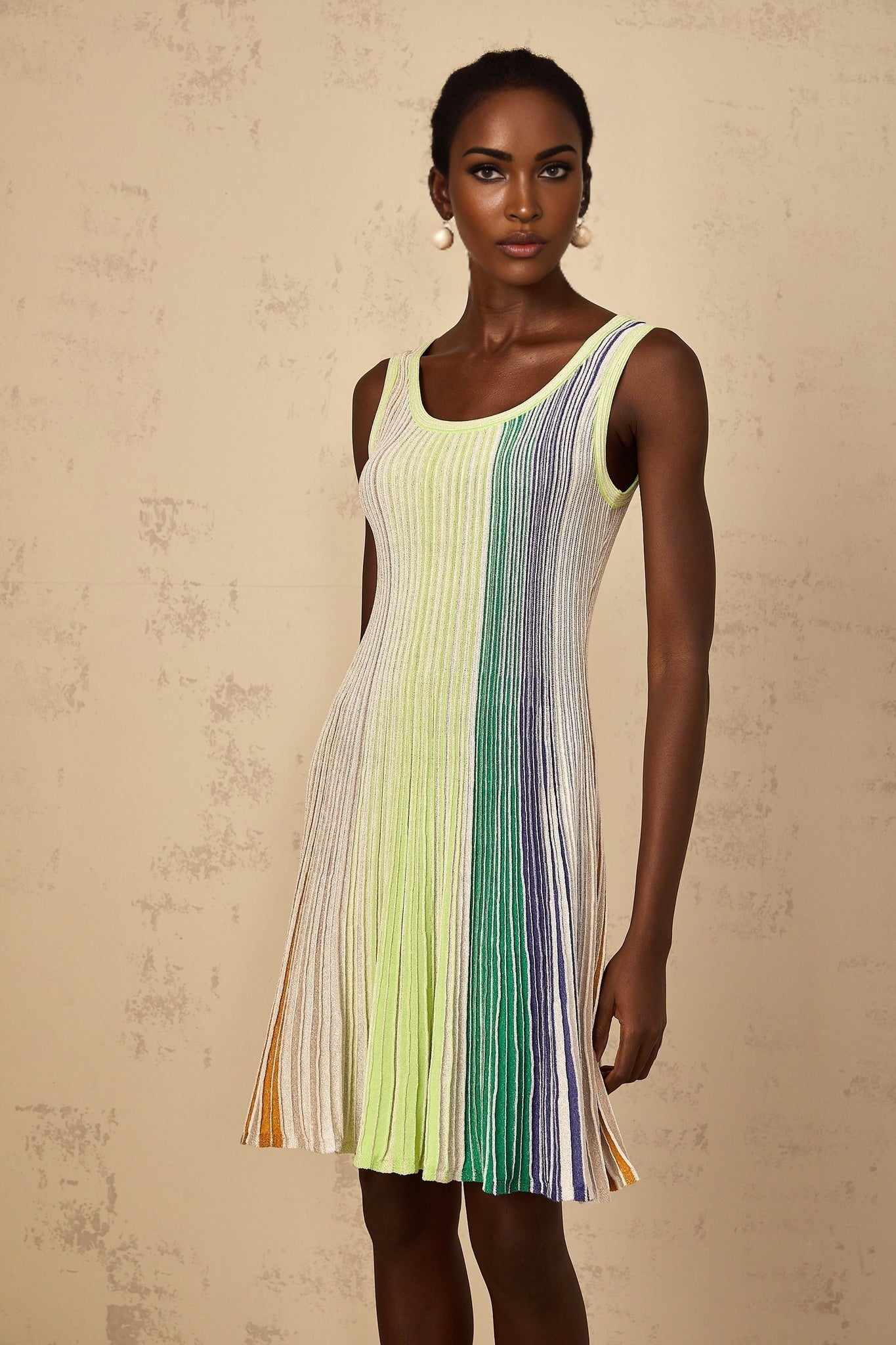 Woman wearing a green mini dress with sequin stripes and knit fabric standing in a neutral pose