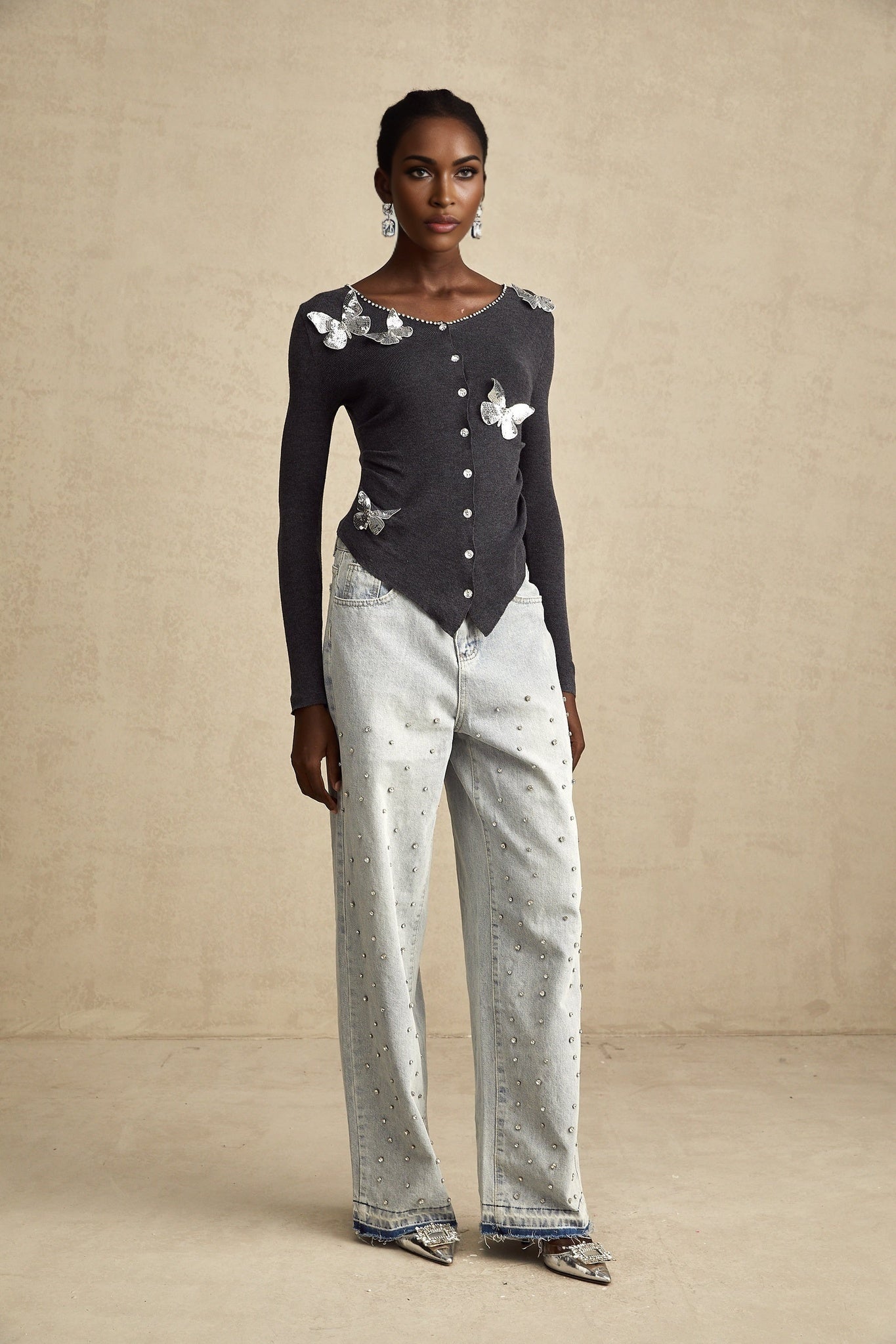 Woman wearing a grey cardigan with sequined butterfly designs on the front