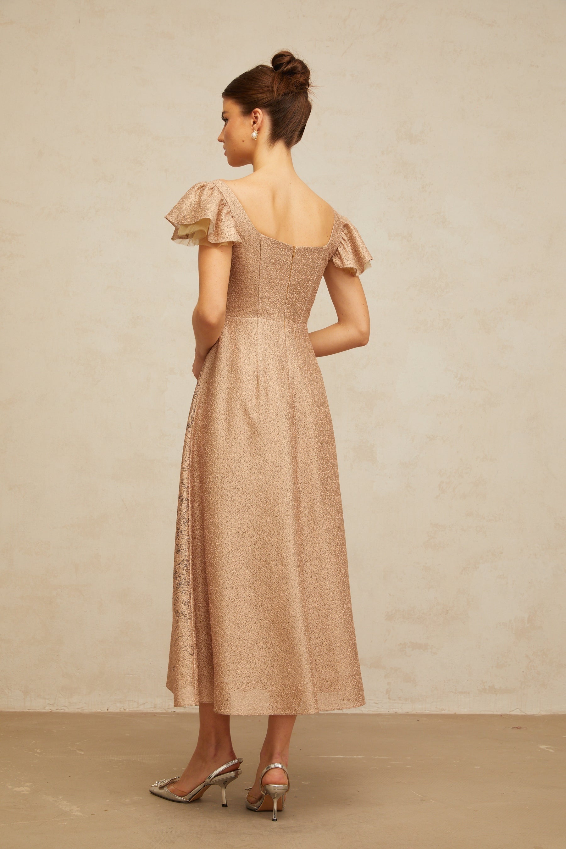 Woman wearing a khaki colored midi dress with graphic print and flared skirt design