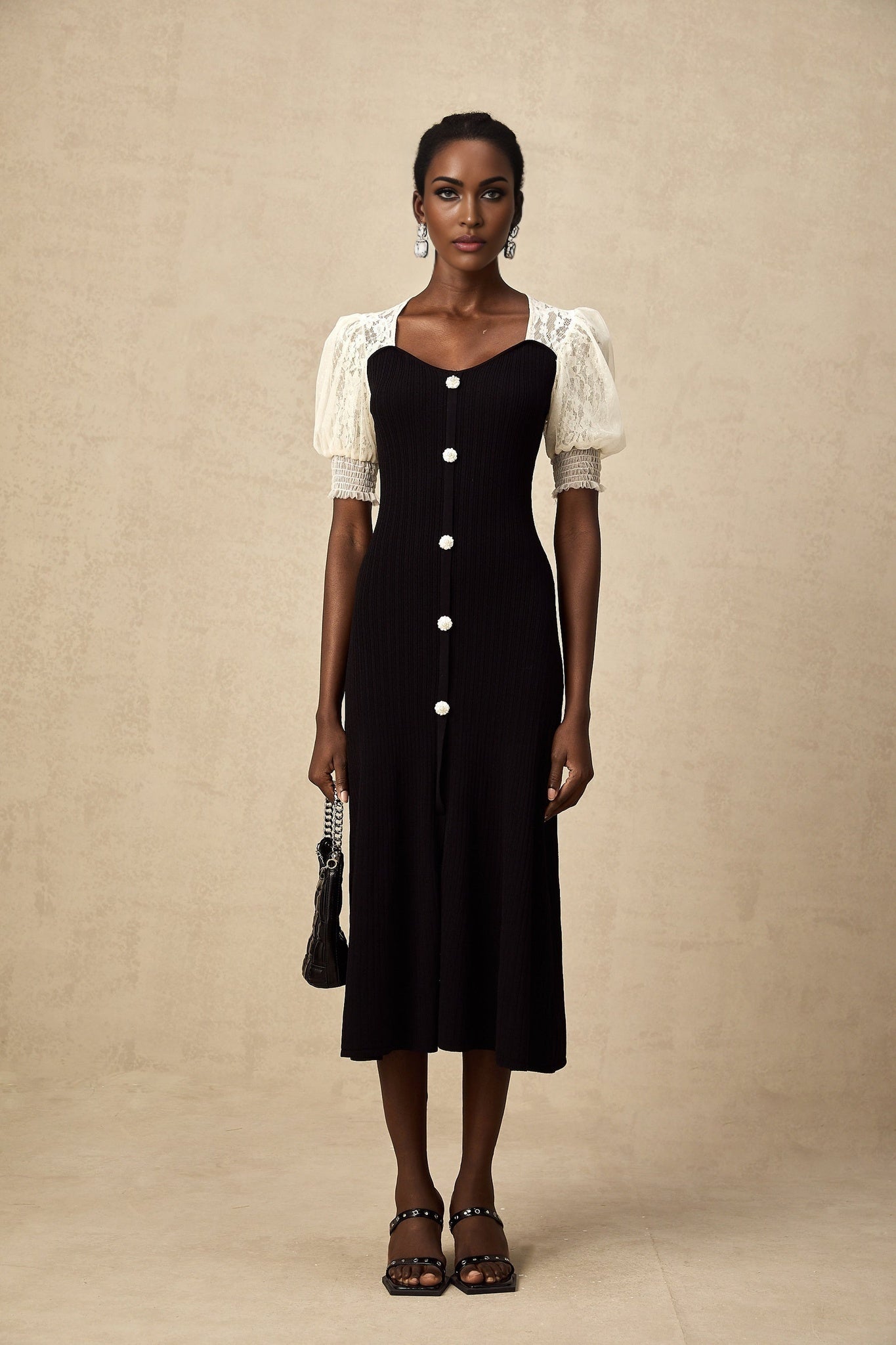 Woman wearing a knit midi dress with lace trim details along the neckline and hem