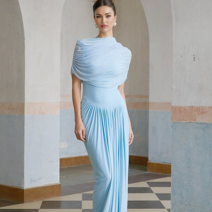Woman wearing a light blue asymmetric pleated maxi dress with flowing fabric and elegant design