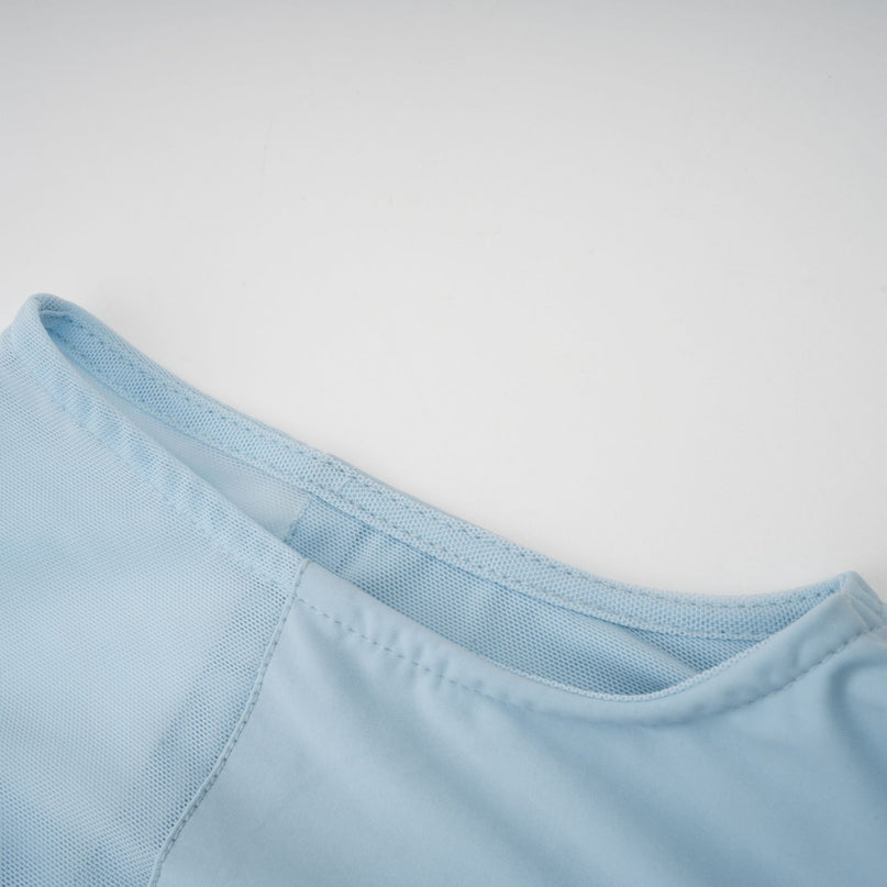 Woman wearing a light blue asymmetric pleated maxi dress with long sleeves and flowing skirt