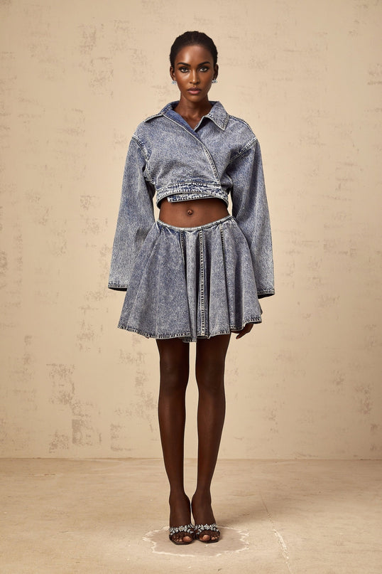 Woman wearing a light blue denim mini skirt with shirred waistband and fitted silhouette