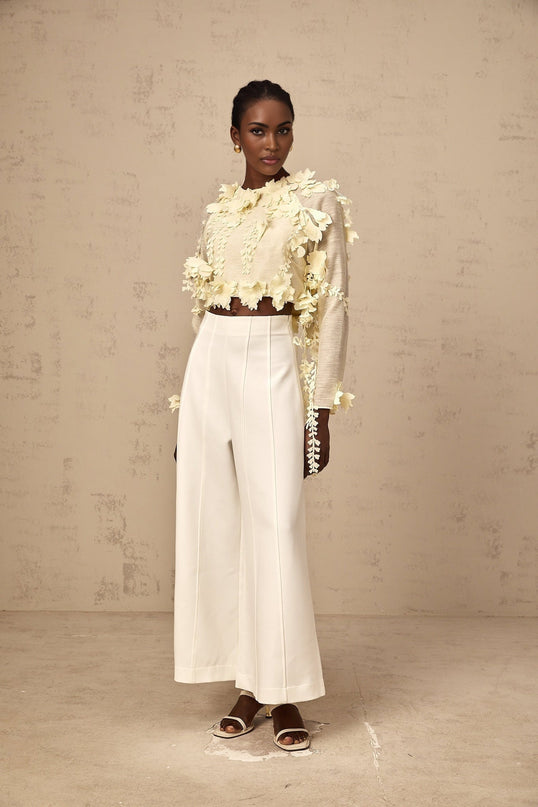 Woman wearing a light yellow cropped blouse with raised 3D petal details on the fabric