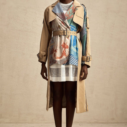 Woman wearing a long belted trench coat with contrasting colors and printed design