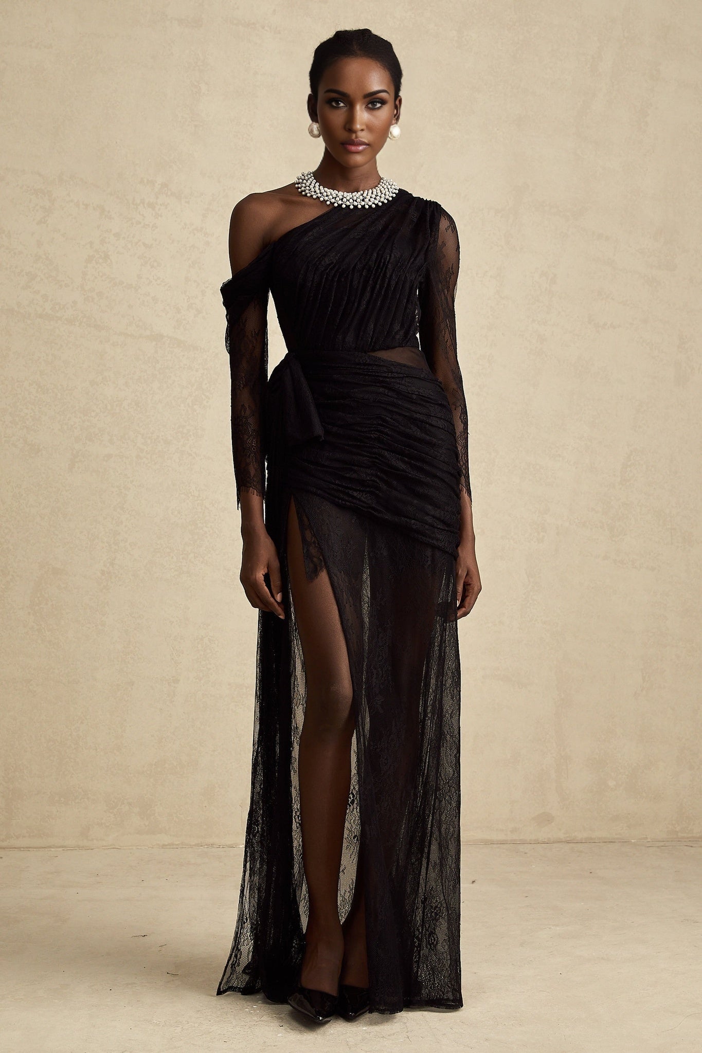 Woman wearing a long black dress with one shoulder strap and a cutout detail on the side