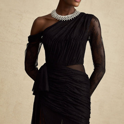 Woman wearing a long black maxi dress with one shoulder strap and cutout detail