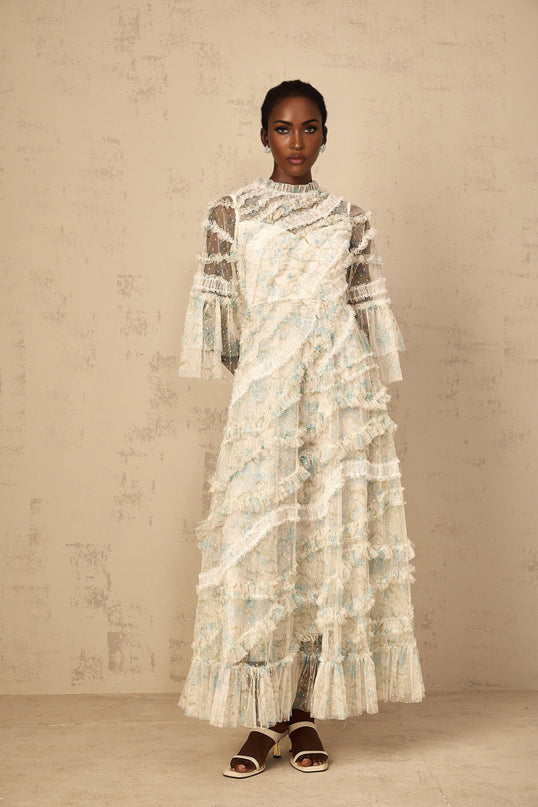 Woman wearing a long blue dress with floral print and ruffled tulle details