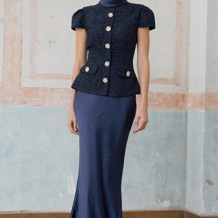 Woman wearing a long blue maxi dress with a fitted peplum waist and panelled design standing in a neutral background