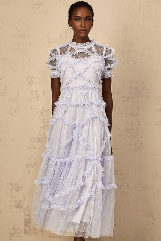 Woman wearing a long blue maxi dress with white polka dots and ruffled tulle details