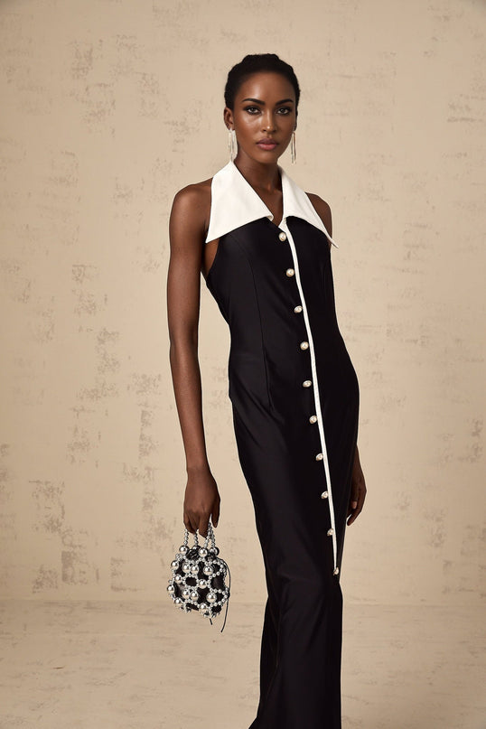 Woman wearing a long fitted maxi dress with colorblocked design in contrasting colors standing in a neutral background