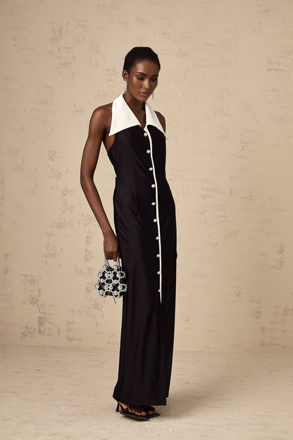 Woman wearing a long fitted maxi dress with colorblocked design in contrasting shades standing against a plain background